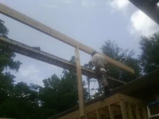 Carpenter setting a ridge beam over a new addition frame — Ice Dam Removal by Roofing Brothers in Glen Campbell