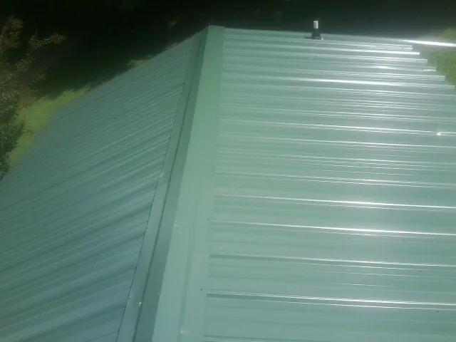 New green metal panels meeting at the ridge of a roof — Flat Roof Repair work by our crew in Glen Campbell