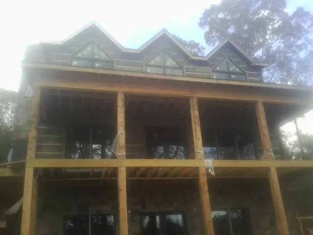Dormers and porch framing on a large log home under construction — Roof Coating work by our crew in Glen Campbell