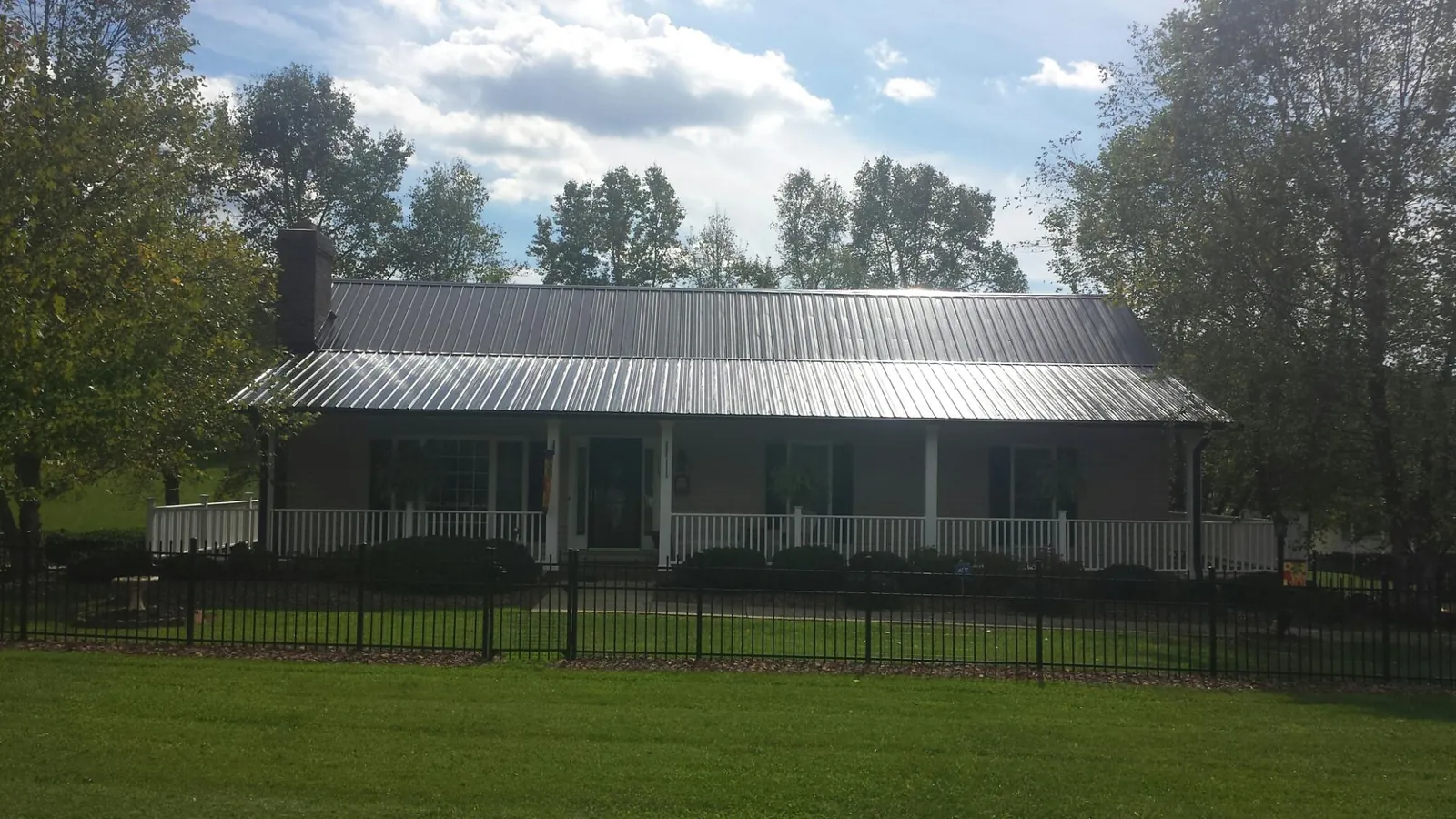 Gray metal roof on a brick ranch with a full width front porch — Gutter Guard Installation work by our crew in Glen Campbell