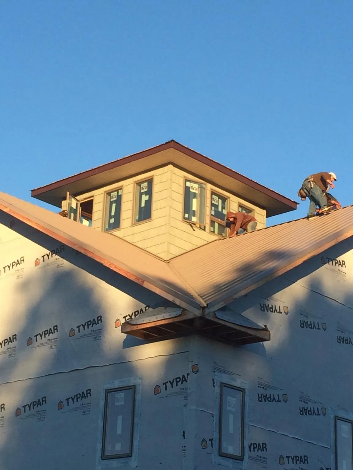 Roofers working around a rooftop cupola on a new metal roof at sunset — Roof Waterproofing in Glen Campbell by Roofing Brothers
